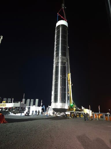 Tall stainless-clad process column standing upright on its foundation after a completed night set