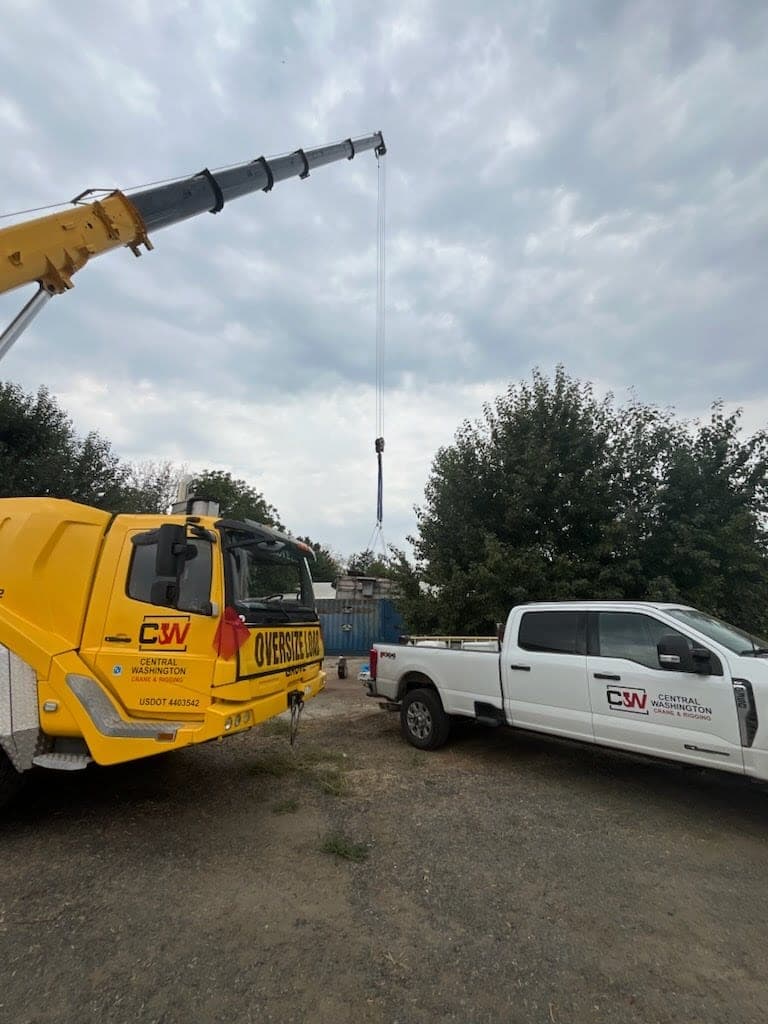 Crane boom extended over a rural jobsite during an equipment placement