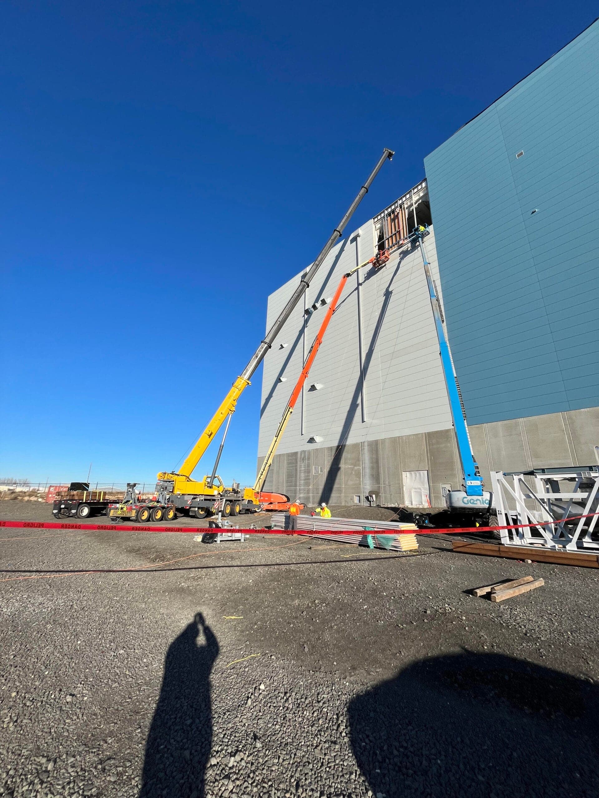Crane crew installing exterior wall panels on a large industrial building