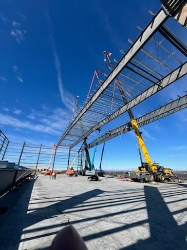 Long steel roof truss suspended by crane during a critical lift on an Eastern Washington jobsite