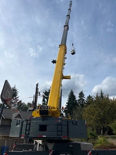 All-terrain crane boomed out with a load on the hook above a residential jobsite