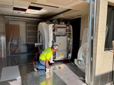 CW Crane & Rigging rigger guiding a heavy medical scanner into its final position inside a facility