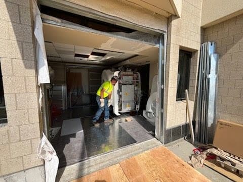 Medical imaging equipment being skated through a temporary wall opening cut for a machinery move