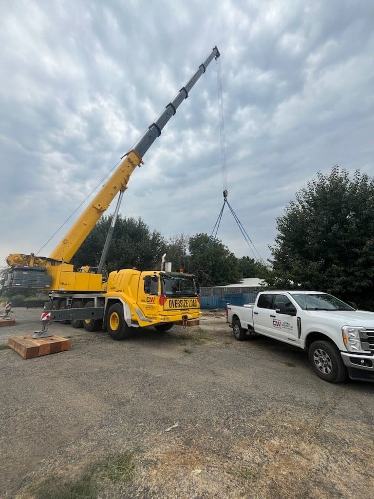 CW Crane & Rigging Grove all-terrain crane boomed out with rigging attached, company service truck alongside