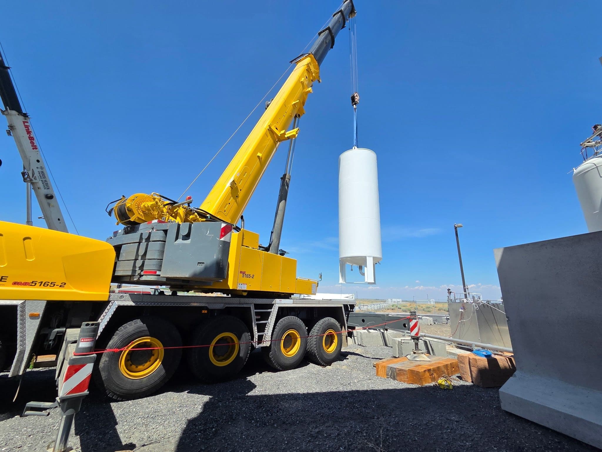 CW Crane & Rigging Grove GMK5165-2 all-terrain crane hoisting a white pressure vessel at an industrial site in Eastern Washington