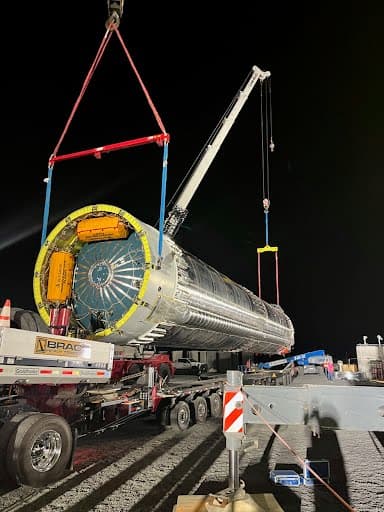Spreader bar and multi-leg rigging attached to the head of a stainless-clad vessel during a night lift